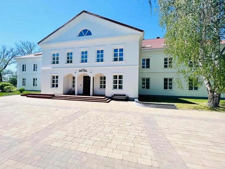 un grande edificio bianco con un albero di fronte di Nad Starą Nidą *** a Pińczów