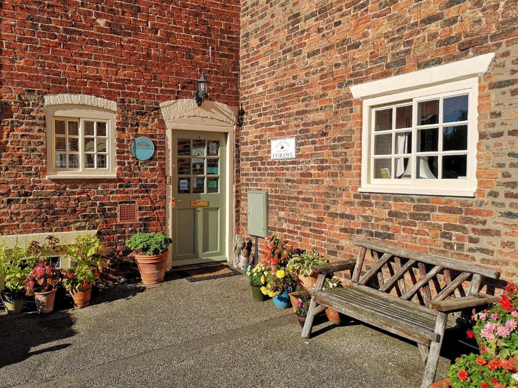 a wooden bench sitting outside of a brick building at Black Swan Guest House in Marton