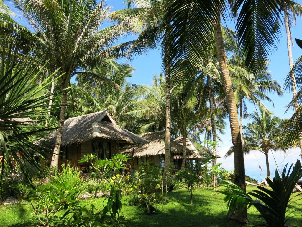 dom na plaży z palmami w obiekcie Camiguin Volcan Beach Eco Retreat & Dive Resort w Mambajao
