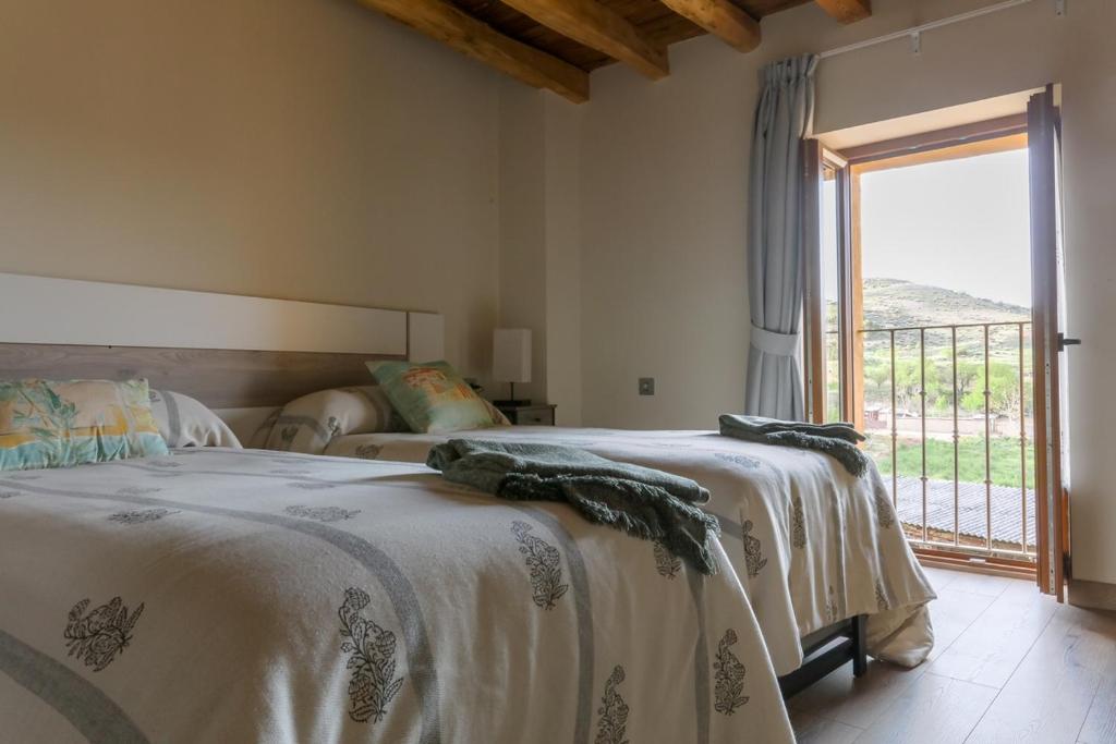 a bedroom with two beds and a large window at Apartamentos turísticos Ribera Natura in San Martín de Rubiales