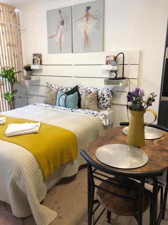 a bedroom with a bed and a table with a yellow blanket at Studio Flat in Wythenshawe