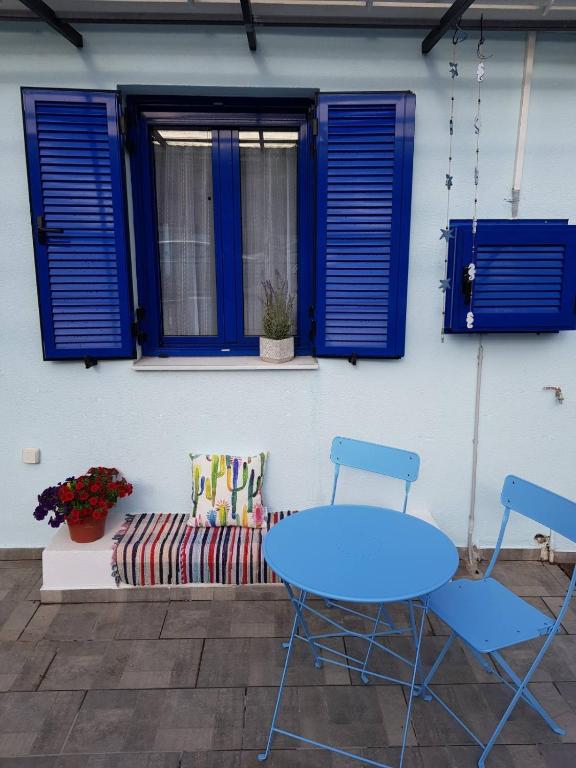 Casa Ble - Izla Homes في سكالا كيفالونياس: فناء مع طاولة زرقاء وكراسي وأريكة