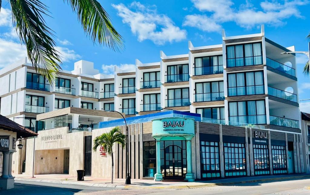 un grand bâtiment blanc avec un palmier en face dans l'établissement Hotel Puerto Libre, à Cozumel