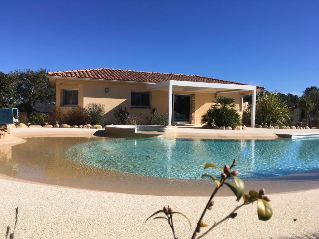 a large swimming pool in front of a house at L'Hacienda Piscine chauffée à 28, spa, boulodrome et court de Tennis privés, 2 villas indépendantes in Porto-Vecchio