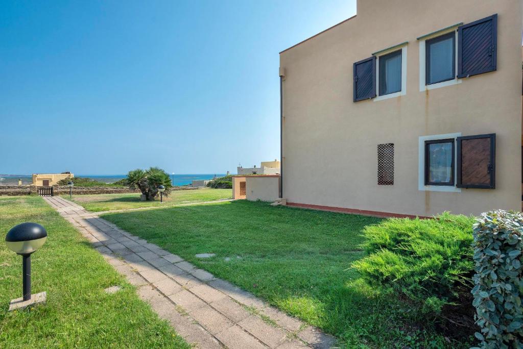 a house with a grass yard next to a building at Pergola 707 in Stintino