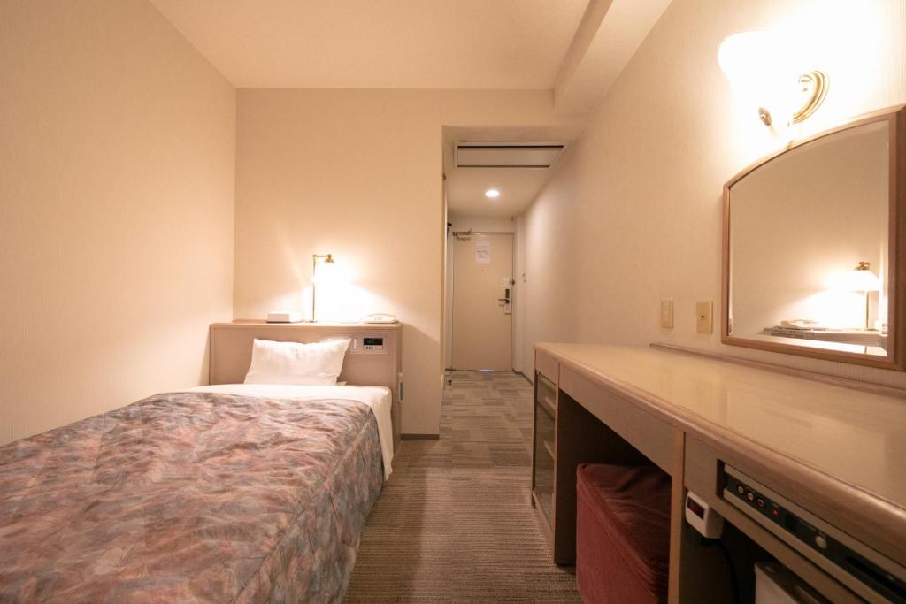 een hotelkamer met een bed en een spiegel bij Main Hotel - Vacation STAY 60460v in Miyakonojo