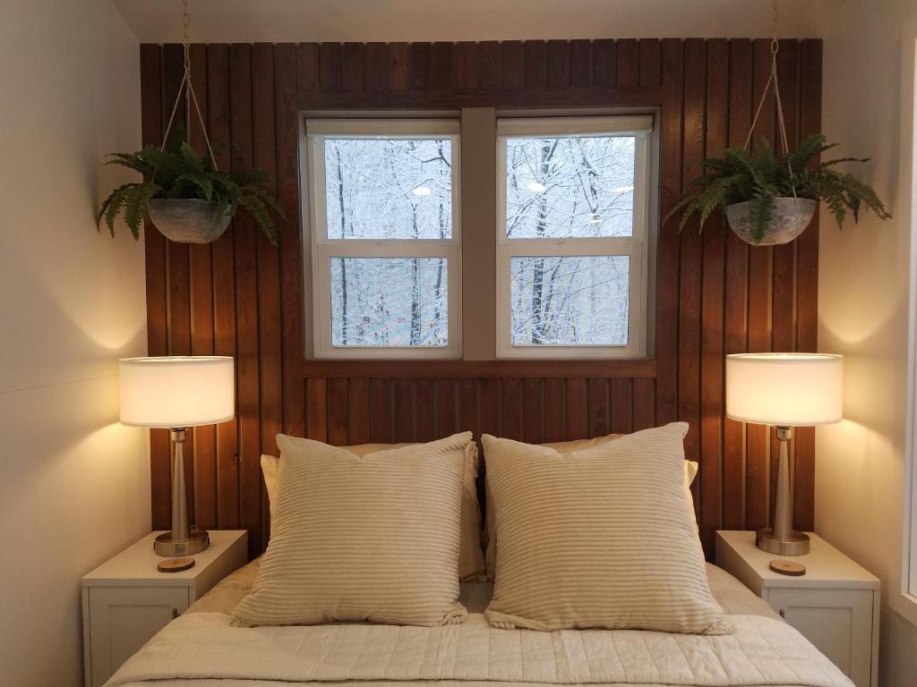 een slaapkamer met 2 ramen en een bed met 2 lampen bij Emerald Little Lodge in Elroy