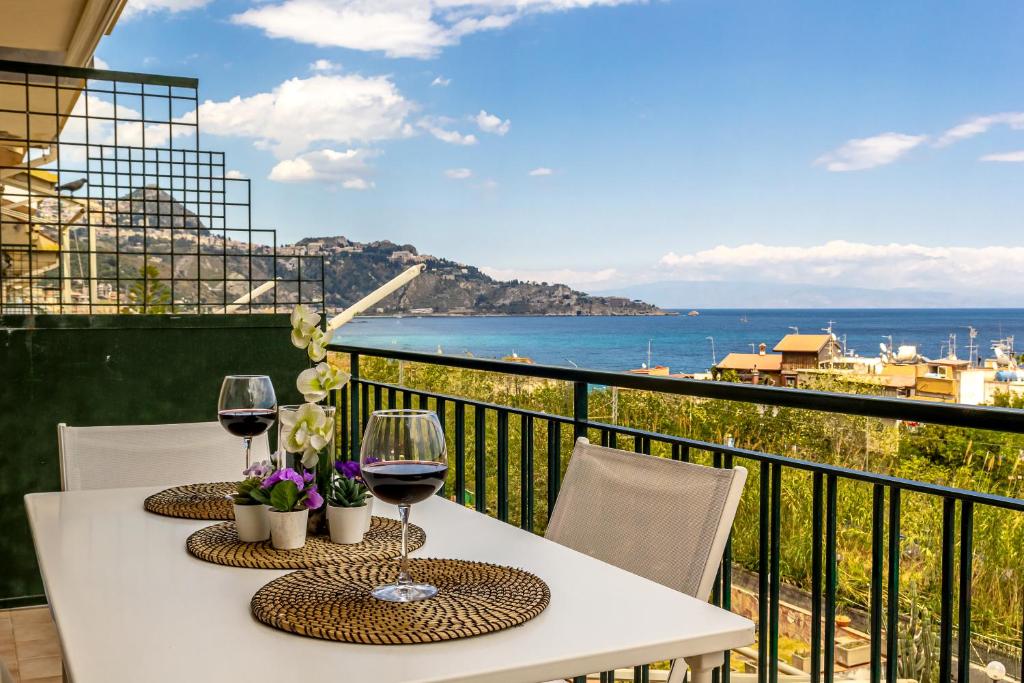 a table with two glasses of wine on a balcony at La Casa Di Stefe in Giardini Naxos