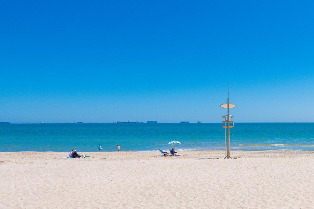 a beach with people sitting on the sand and the ocean at Salamar Saler Golf in El Saler