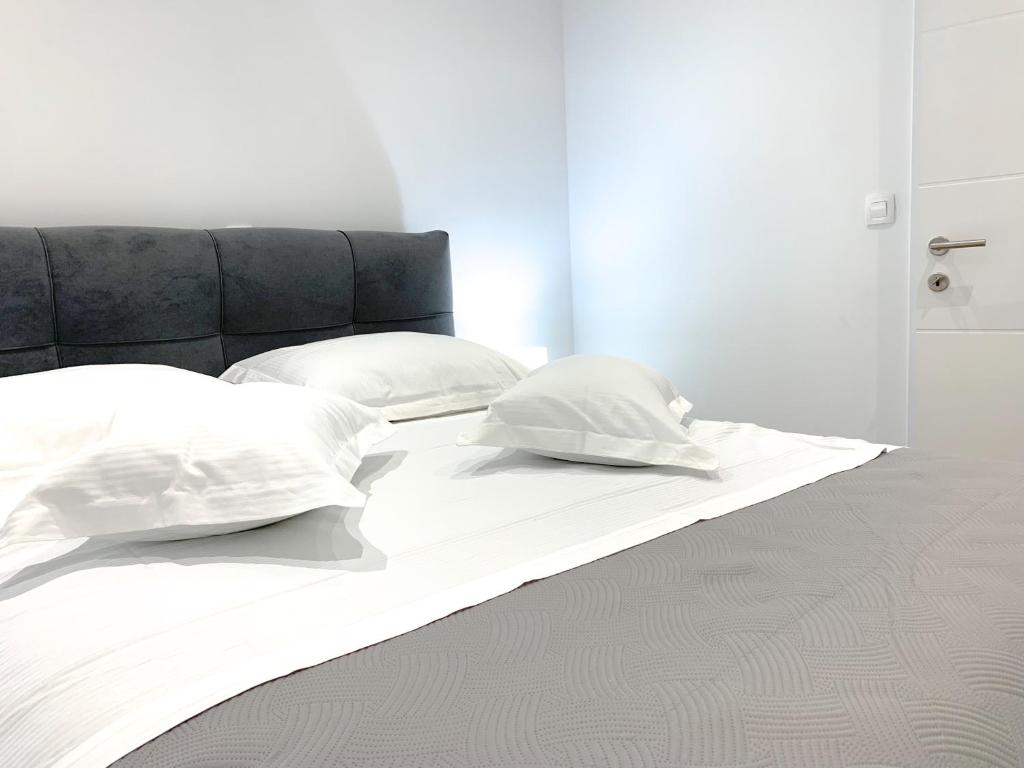 ein weißes Bett mit zwei Kissen darüber in der Unterkunft G Apartment in Podstrana