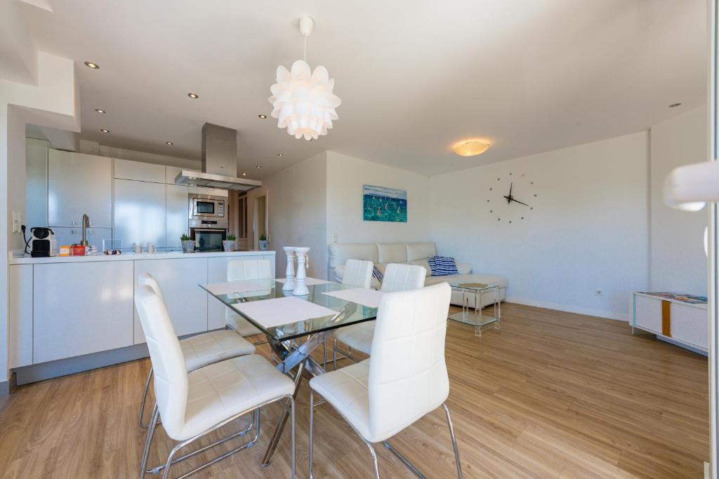 a kitchen and dining room with a glass table and white chairs at Salamar Saler Golf in El Saler
