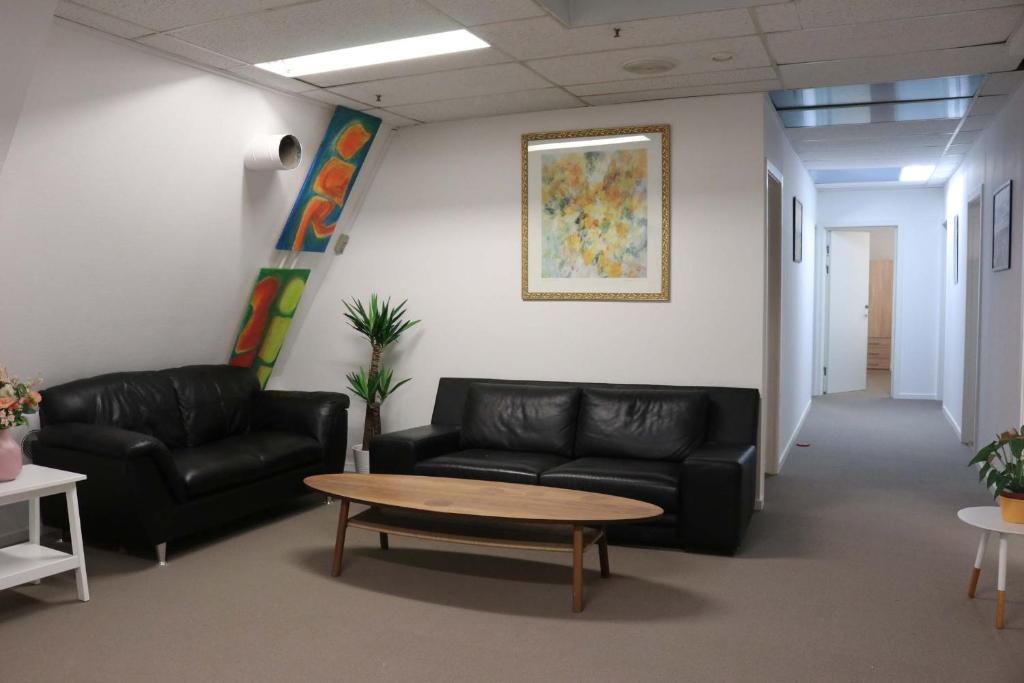 a waiting room with black leather couches and a coffee table at Budget Rooms Copenhagen in Ishøj