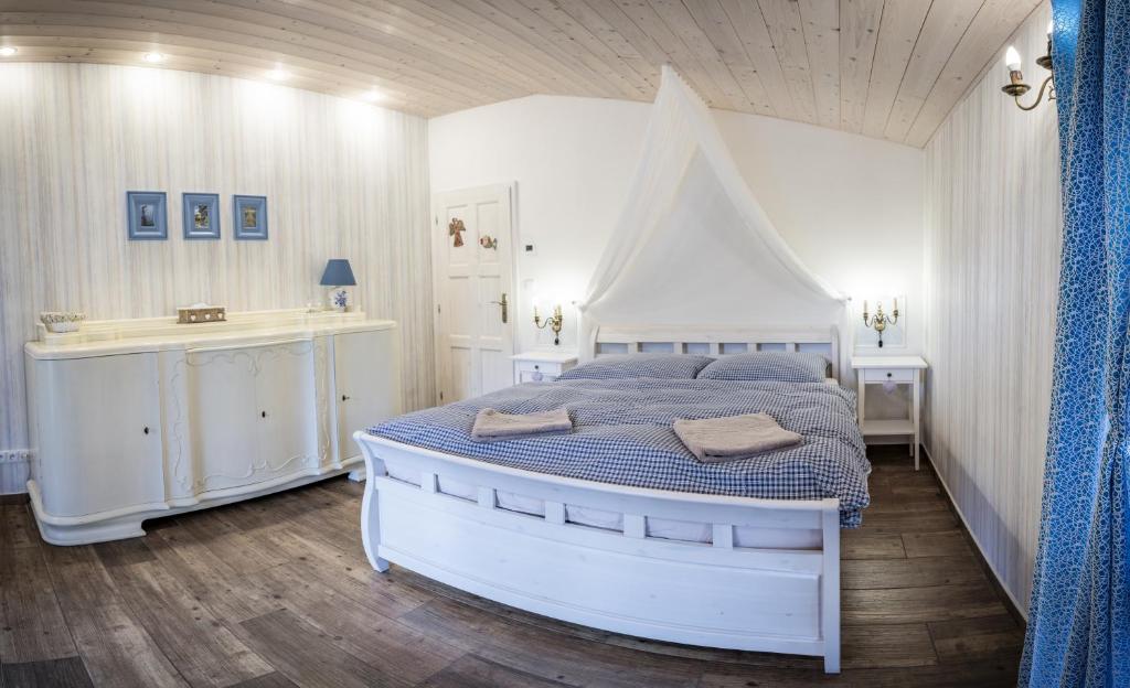 a white bedroom with a bed and a sink at Penzion Primášé in Dolní Věstonice