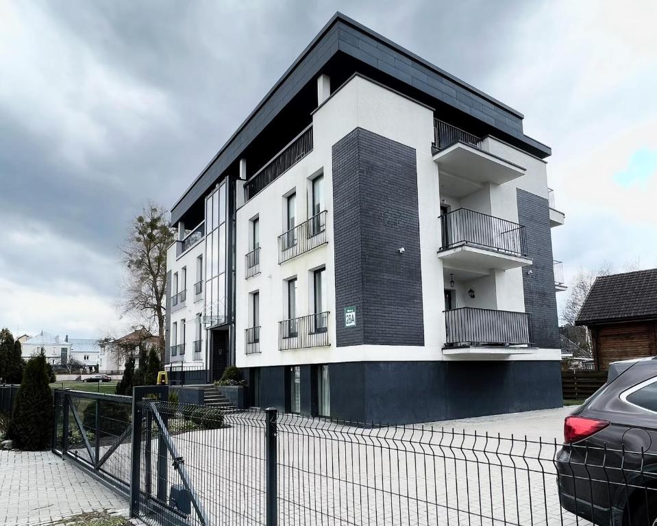 a white and black building with a fence in front of it at Centre Apartment in Druskininkai