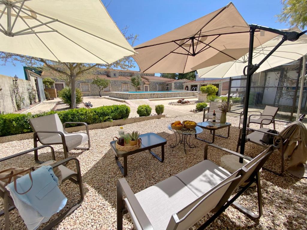 un patio con sillas, mesas y sombrillas en ESSE NATURA alojamientos & lifestyle en Pozohondo