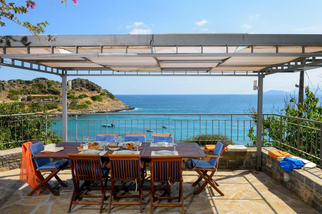 a table and chairs on a patio with a view of the ocean at Ammoudara Bay Villa in Agios Nikolaos