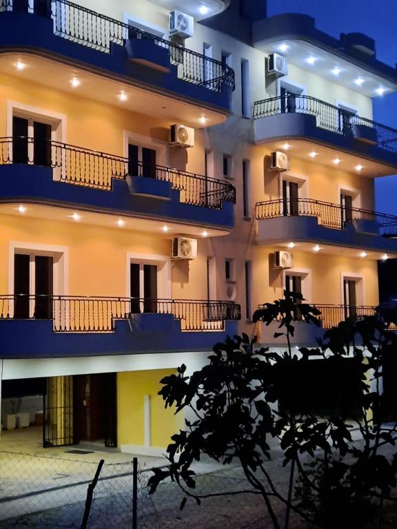 un edificio con balcones azules por la noche en Amarildo Hotel, en Himare