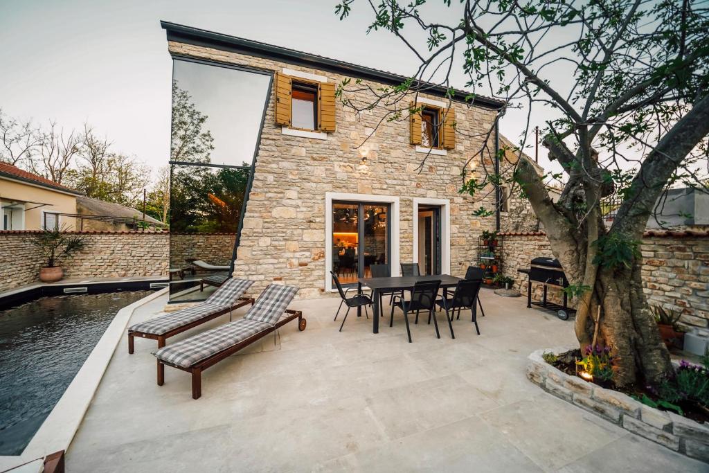 patio ze stołem i krzesłami oraz budynek w obiekcie Casa Giulia with heated pool w mieście Privlaka