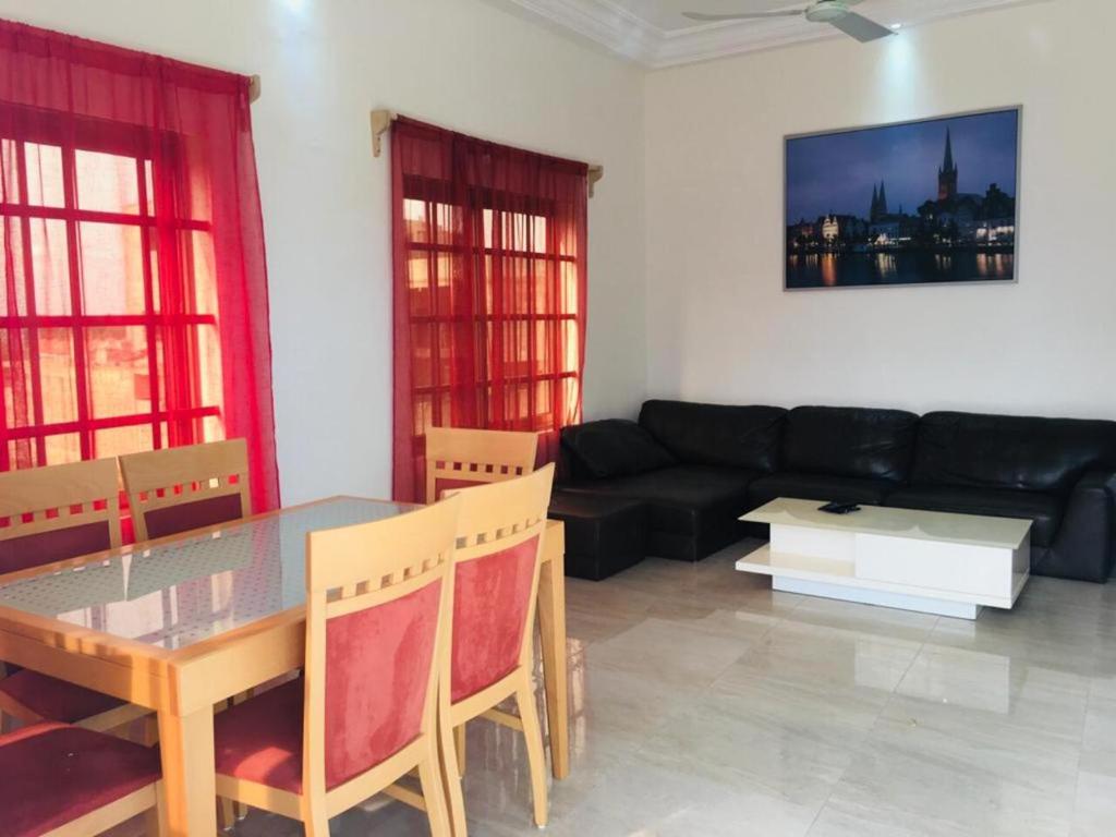 ein Wohnzimmer mit einem Tisch und einem schwarzen Sofa in der Unterkunft Villa Cocotiers A11 in Cotonou