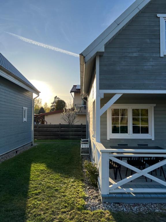 a gray house with a porch and a yard at Domki Skandynawskie Kopalino in Kopalino