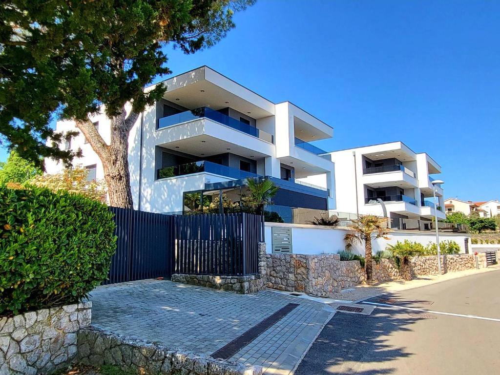 a large white building with a fence in front of it at Modern Apartments Elle Malinska in Vantačići