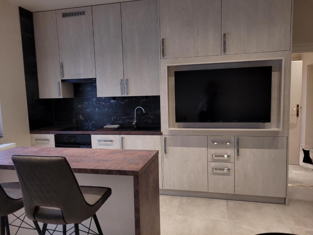 eine Küche mit einem TV sowie einem Tisch und Stühlen in der Unterkunft Lara II Apartman in Debrecen