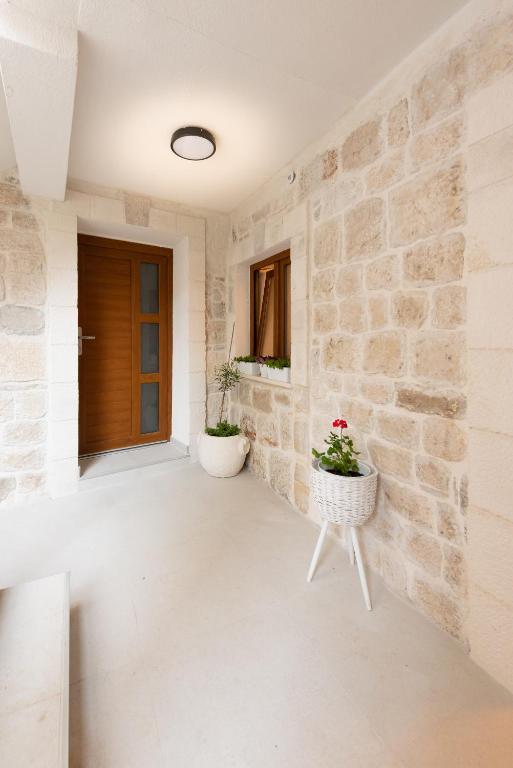 a room with a stone wall and two potted plants at Apartment Olive in Kaštela