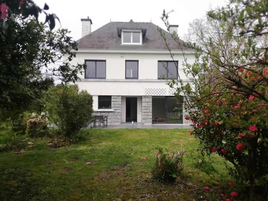 una gran casa blanca con un patio con árboles en Grande maison familiale, Concarneau, en Trégunc