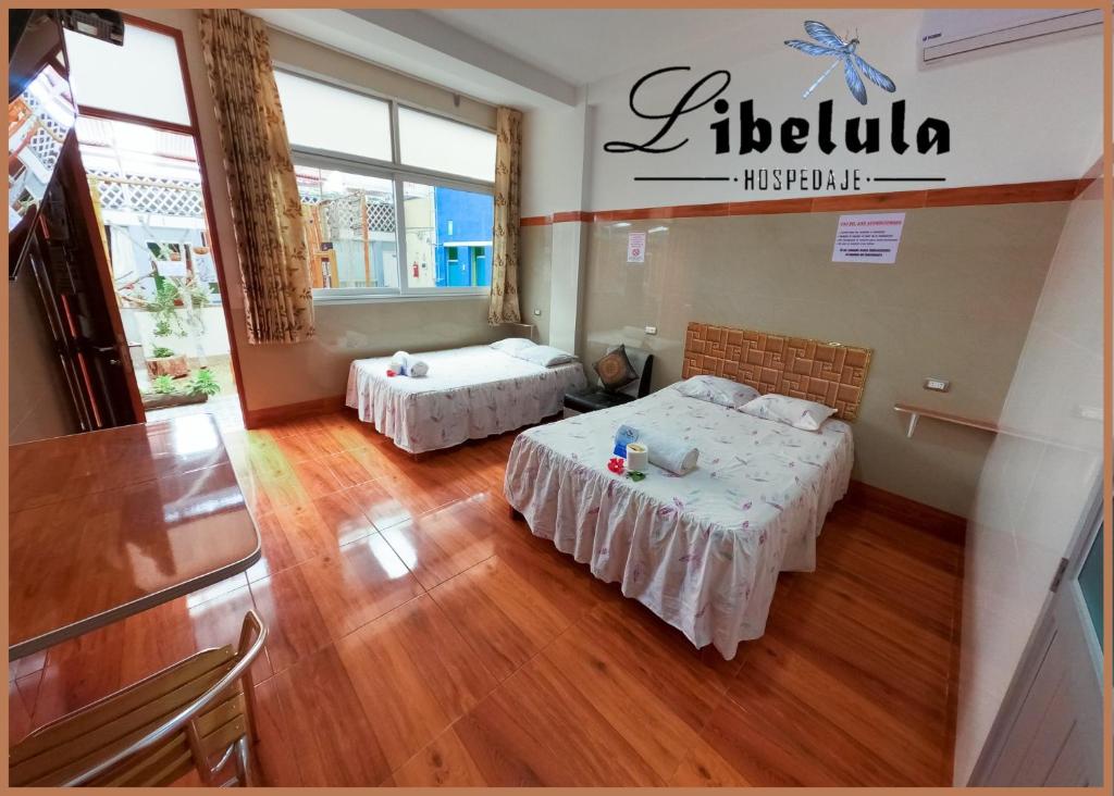 twee bedden in een kamer met houten vloeren bij Libélula Hospedaje in Puerto Maldonado