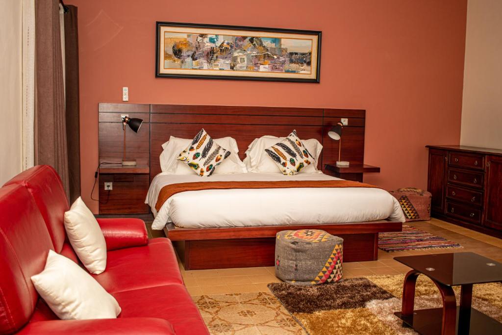 um quarto com uma cama e um sofá vermelho em Résidence Hôtelière Lauria em Lomé