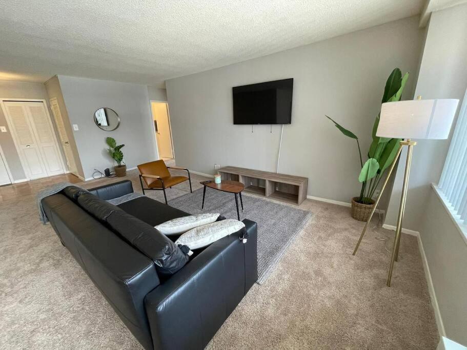 a living room with a black leather couch and a flat screen tv at Trendy and Adaptable Accommodation in Crystal City in Arlington