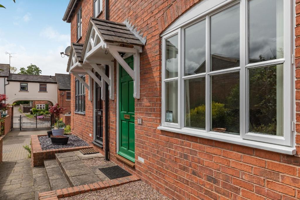 a brick house with a green door and windows at 4 Aldelyme Court in Audlem