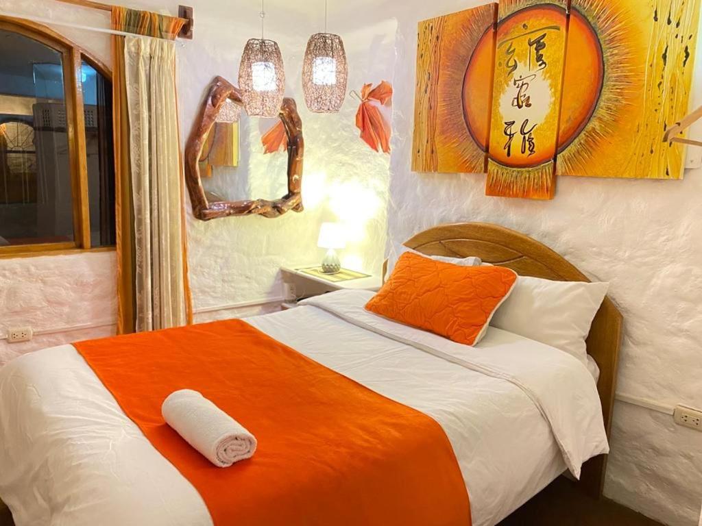 Hostal Madre Tierra في كوسكو: غرفة نوم بسرير وبطانية برتقالية بيضاء