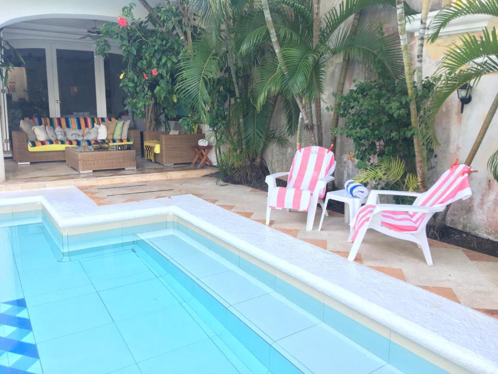 a swimming pool with two chairs and a table at La Villa du Golf à Cancun Hotel Boutique in Cancún