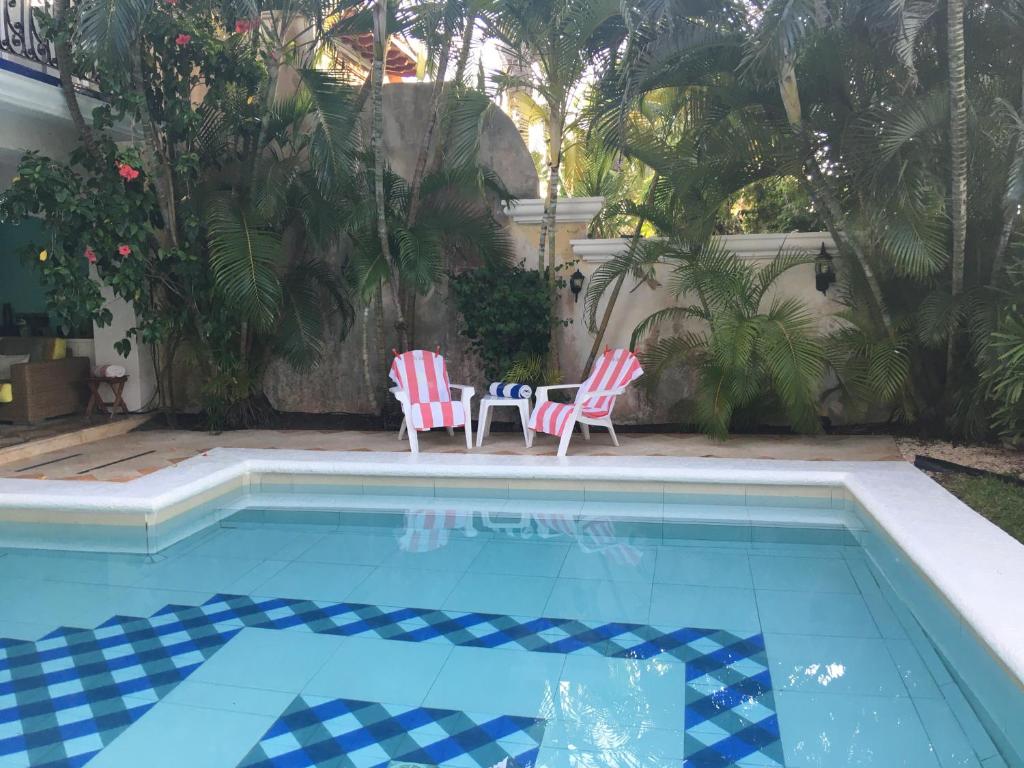 two chairs and a table next to a swimming pool at La Villa du Golf à Cancun Hotel Boutique in Cancún