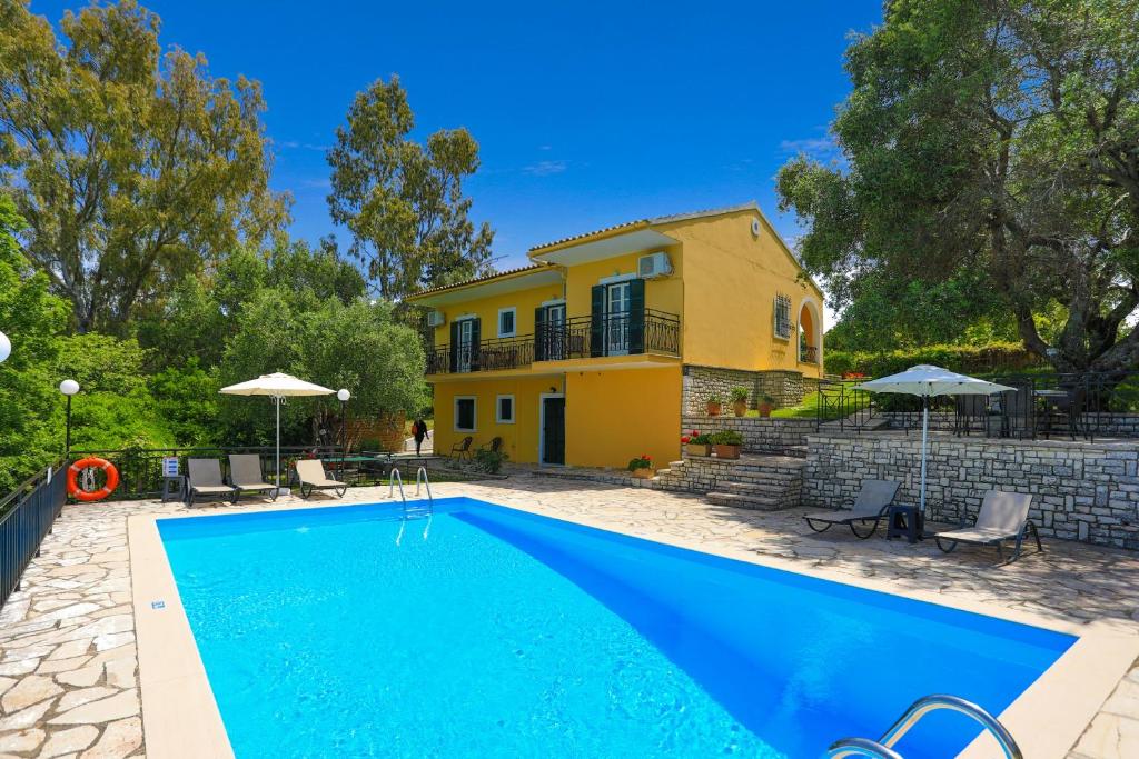 a villa with a swimming pool in front of a house at Villa Joanna in Ágios Stéfanos