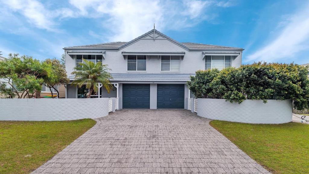 a white house with a blue garage at Red Rock in Yamba