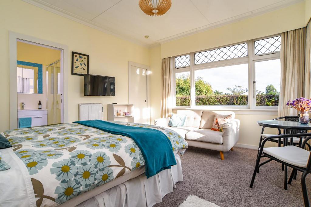 een slaapkamer met een bed en een bank bij Sunny Mornington 2 Bedroom Guest Suite in Dunedin