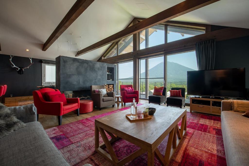 a living room with a large tv and red chairs at Akatsuki in Niseko