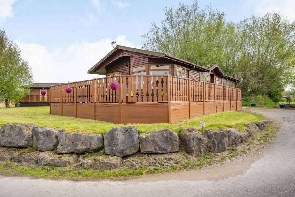 a large wooden cabin with rocks around it at Lakeview Lodge in Carnforth