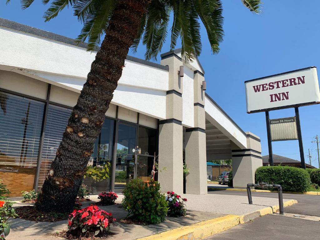 
a large palm tree is in front of a store at Western Inn - Pensacola in Pensacola
