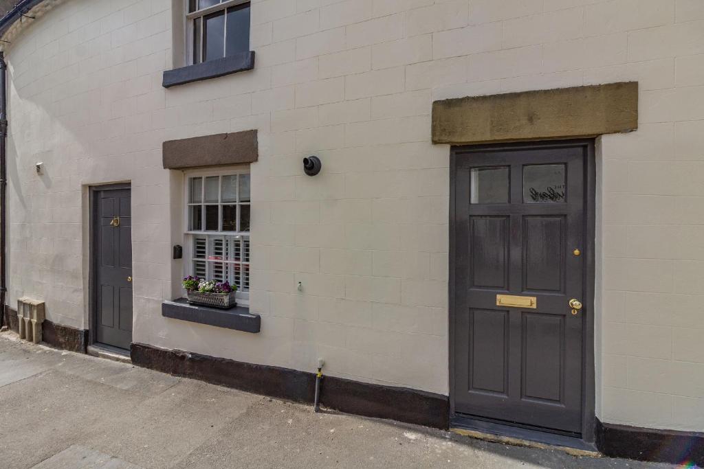 a building with two doors and a window with flowers at Saddlers Cottage in Matlock