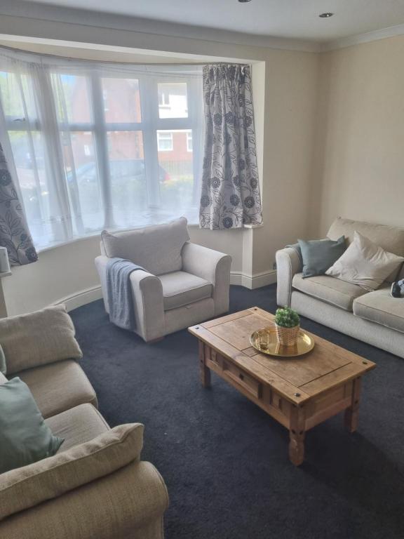 a living room with couches and a coffee table at Lovely residential home 2 bed apartments in Goodmayes