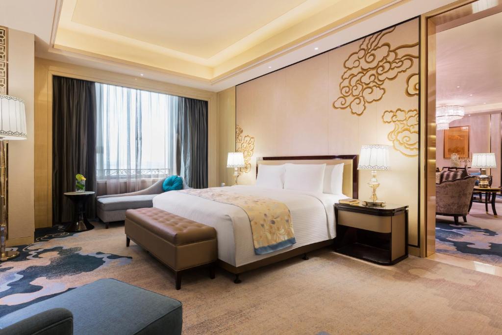 a hotel room with a bed and a living room at Wanda Realm Chifeng Hotel in Chifeng
