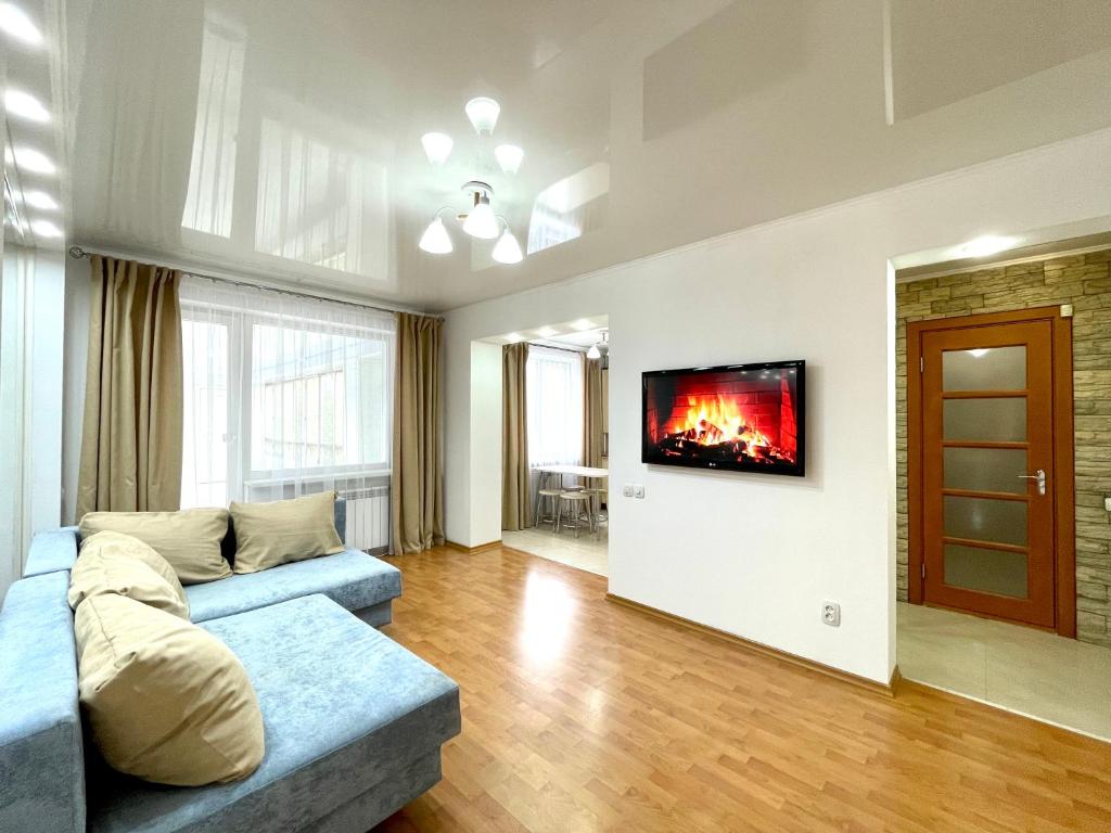 sala de estar con sofá y TV en la pared en Букетова 65 2-комн квартира с гостиничным сервисом с белым постельным, en Petropavlovsk