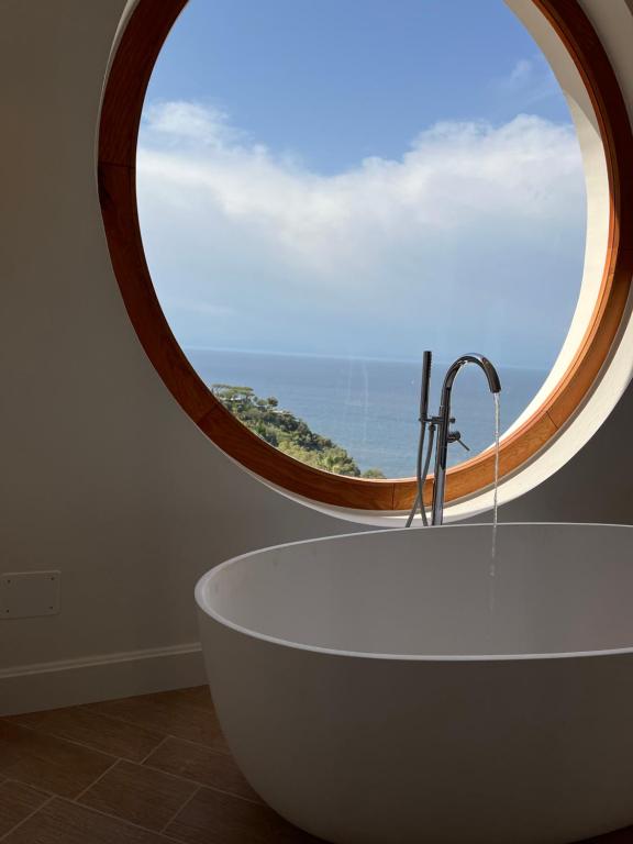 un bagno con una grande finestra rotonda e una vasca da bagno di Agapanto Luxury Accommodation a Ischia