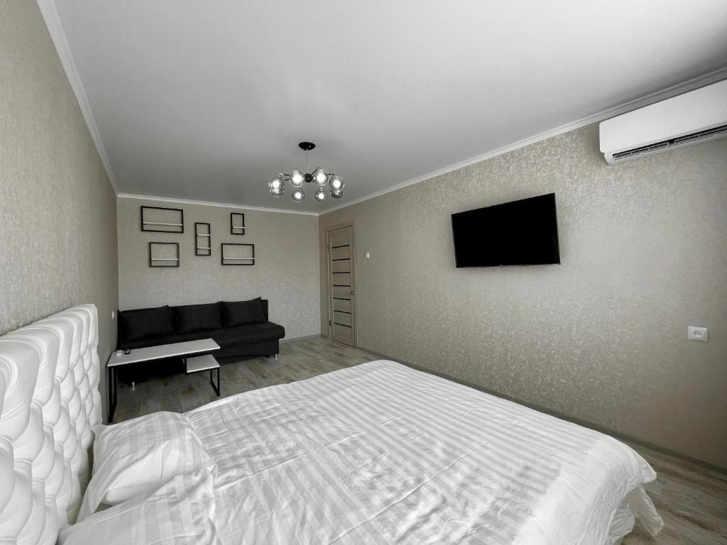 1 dormitorio con 1 cama y TV de pantalla plana en Стильная квартира с кондиционером, en Petropavlovsk