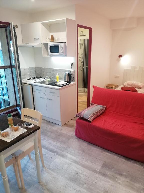 sala de estar con sofá rojo y cocina en Charmant logis au coeur de Mirepoix, en Mirepoix