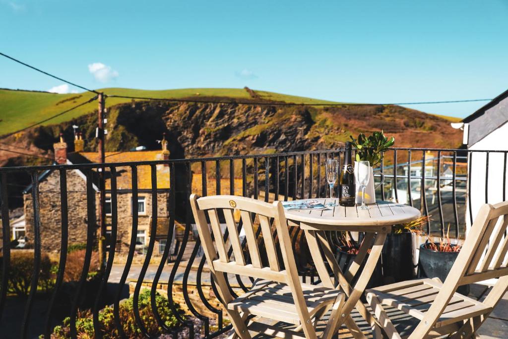 a table and chairs sitting on a balcony with a view at Stowaway, Port Isaac Bay Holidays in Port Isaac