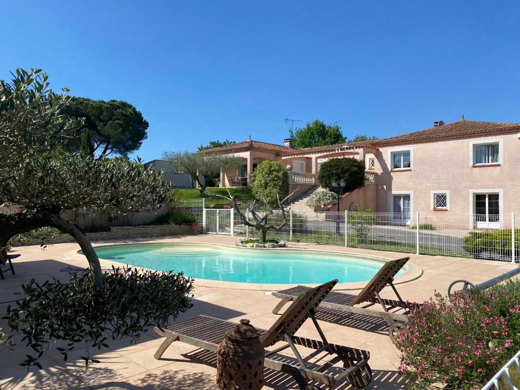 - une piscine avec 2 chaises et une maison dans l'établissement Gîte du Mercadal Les Pujols, à Pamiers